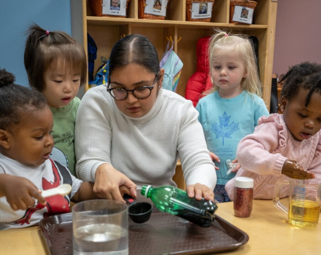 Teacher conducting experiment with for children sitting beside her