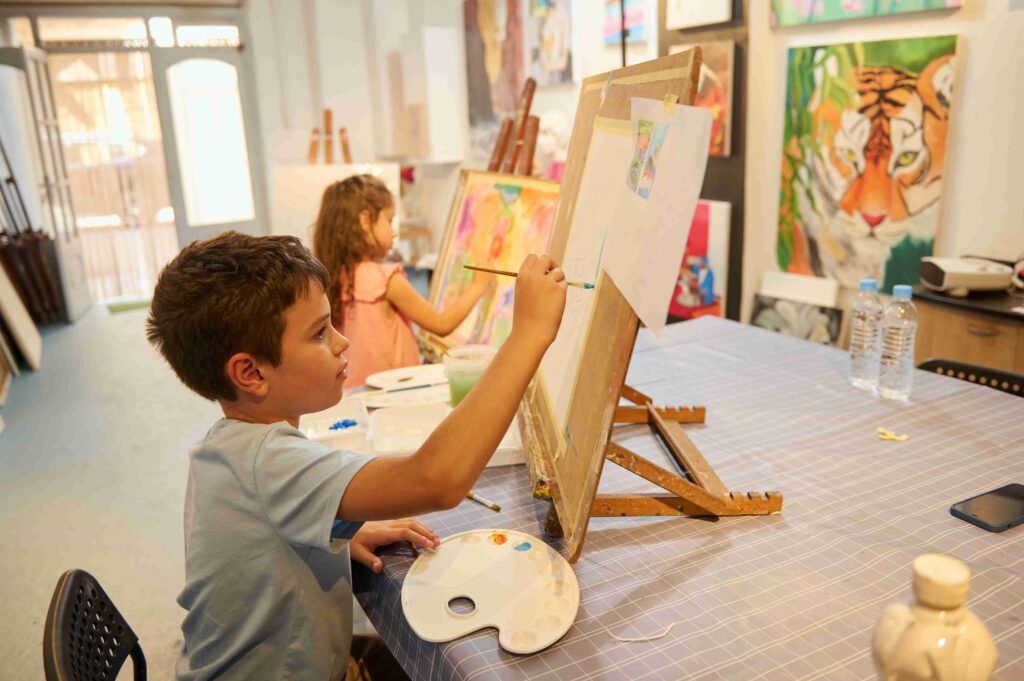Cover image representing a boy and a girl painting in a painting studio at The Learning Nest