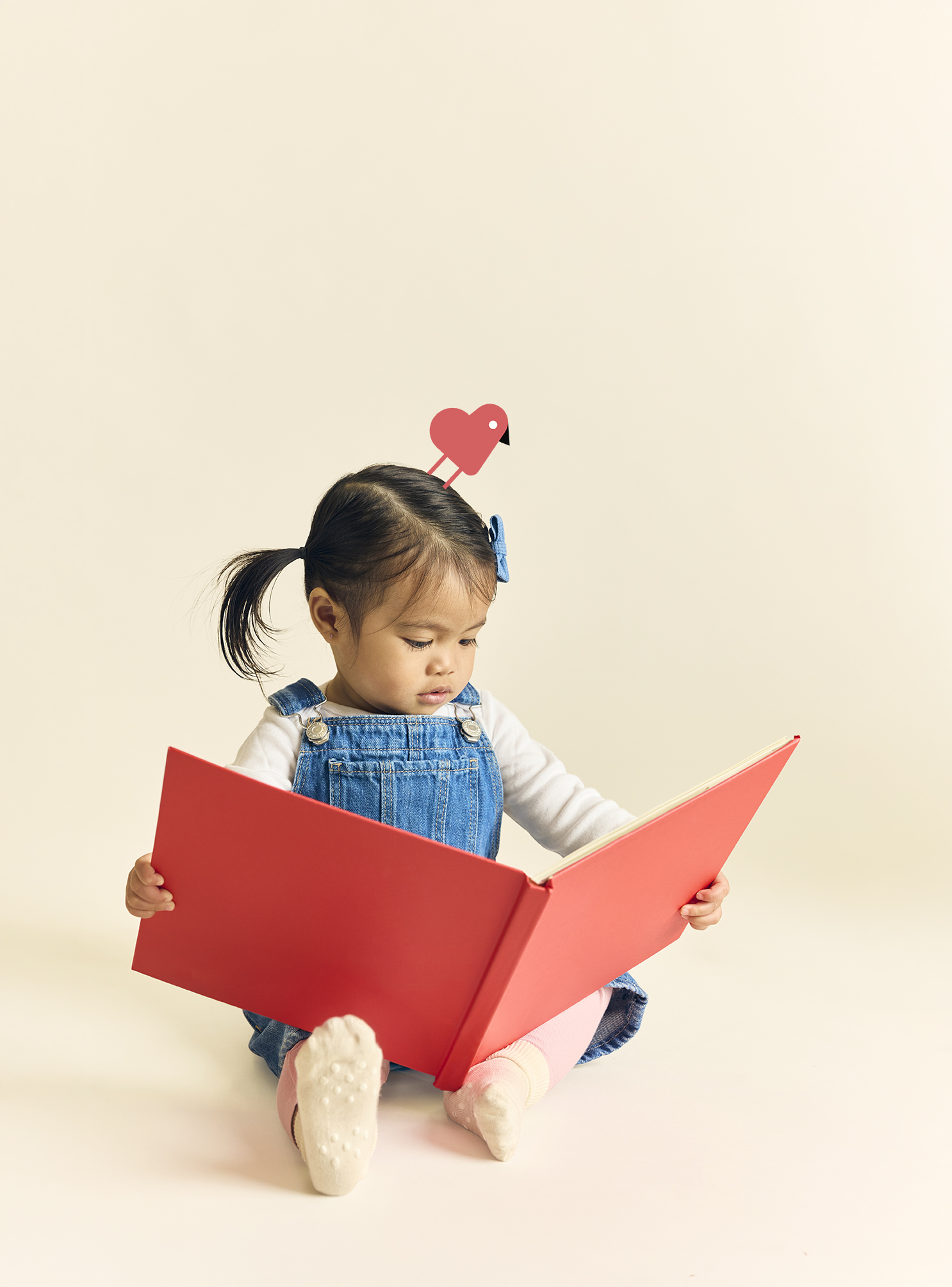 Girl sitting and reading a book, involved in learning activities following the HighScope curriculum at The Learning Nest