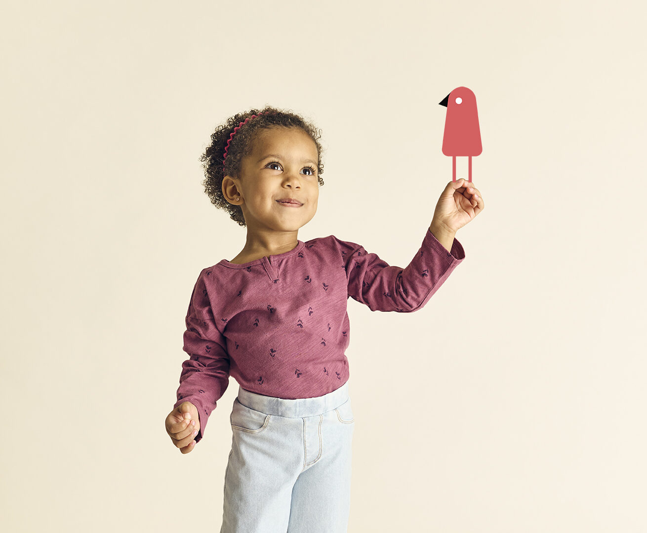 Preschool girl holding the bird from the The Learning Nest logo