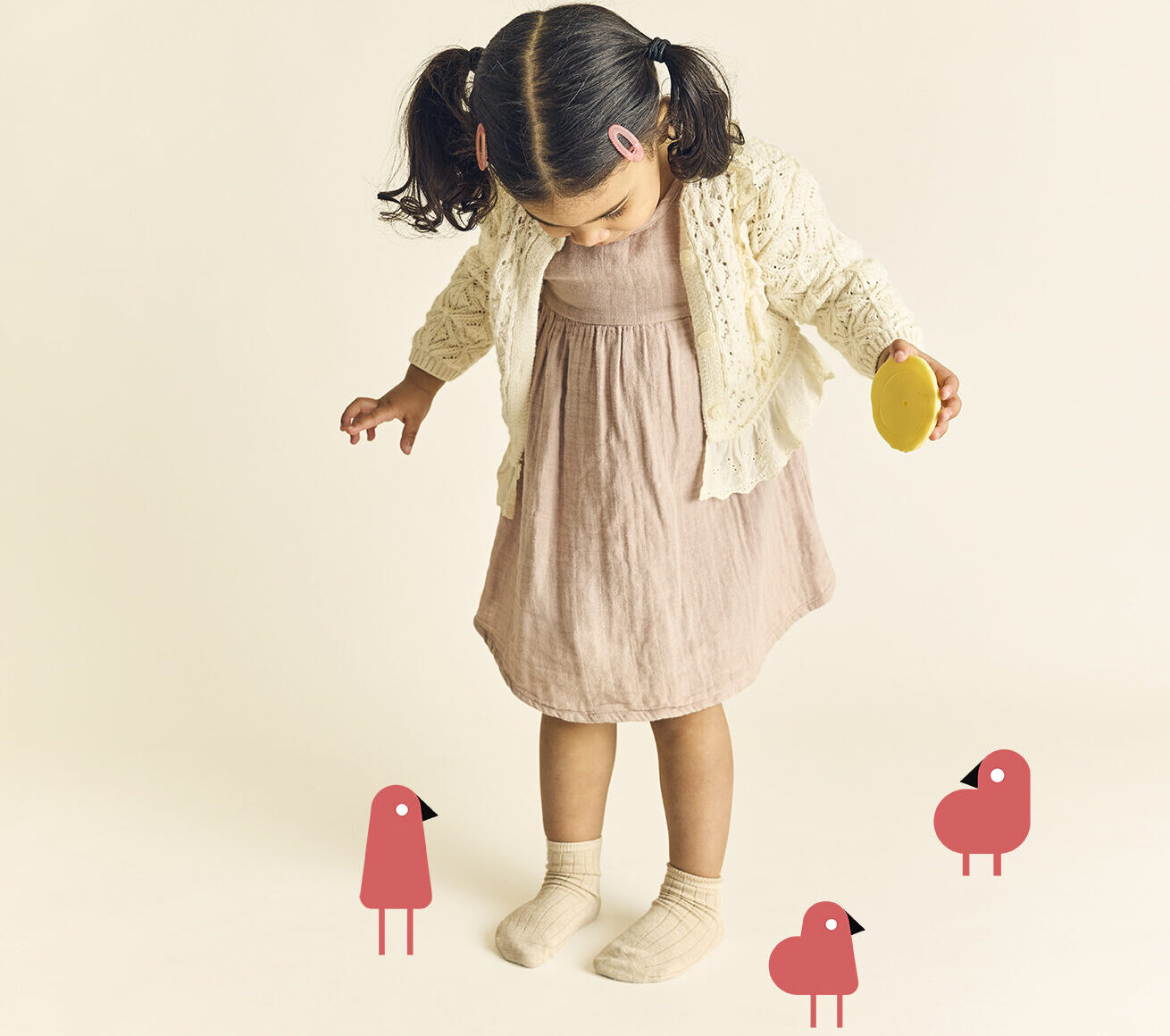 Child holding a cookie looking down at her feet showing participation in early learning activities at The Learning Nest