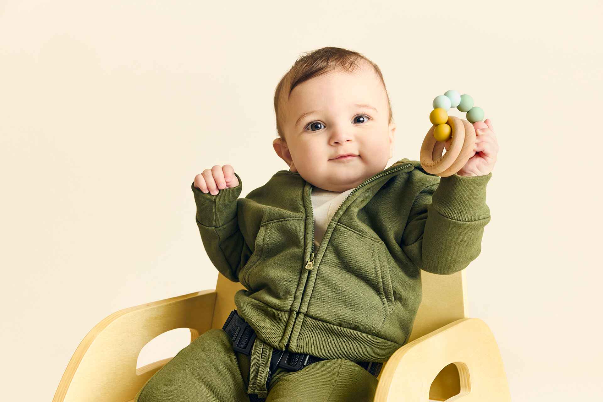 Infant sitting in a cozy chair holding a toy at The Learning Nest's infant daycare program