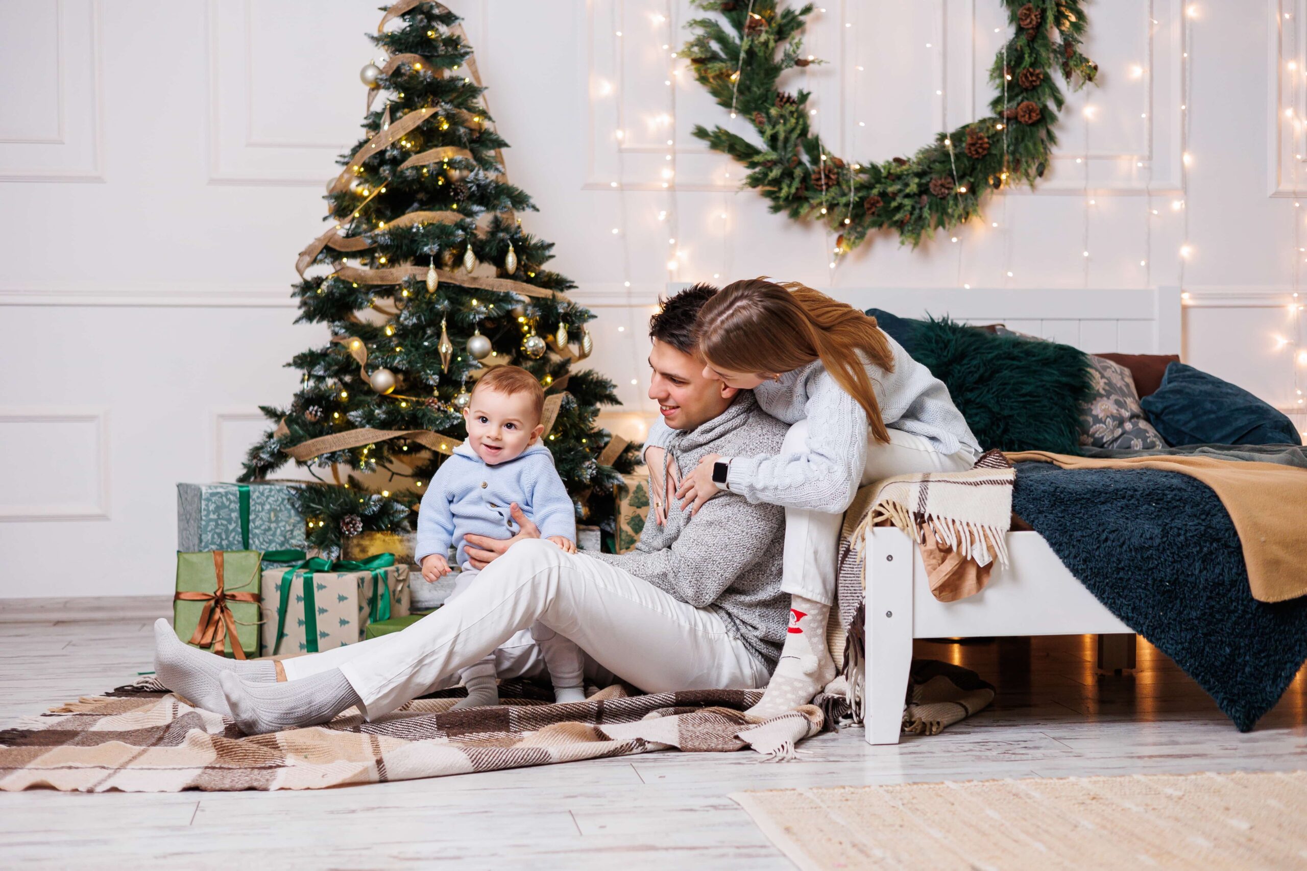 Parents with their toddler in front of a Christmas tree on Christmas Eve